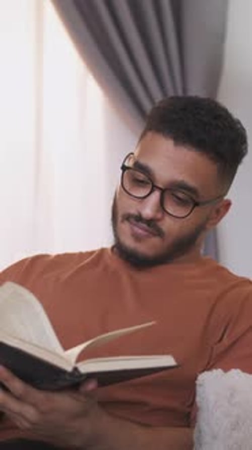Man Reading Book Indoors in Home Setting