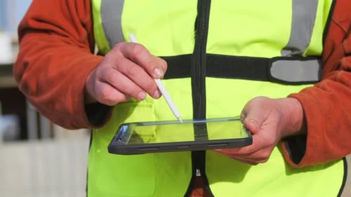 Close up engineer builder with a tablet in his hands writing with stylus checking blueprint building