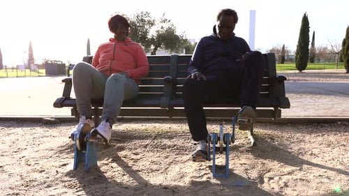 senior couple exercising in an outdoor gym sitting on a bench