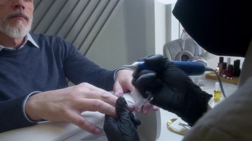 Mature Man Receives Manicure at Nail Salon