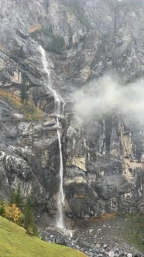 Uma majestosa cachoeira montanhosa desce graciosamente por uma paisagem nebulosa de serenidade na Suíça