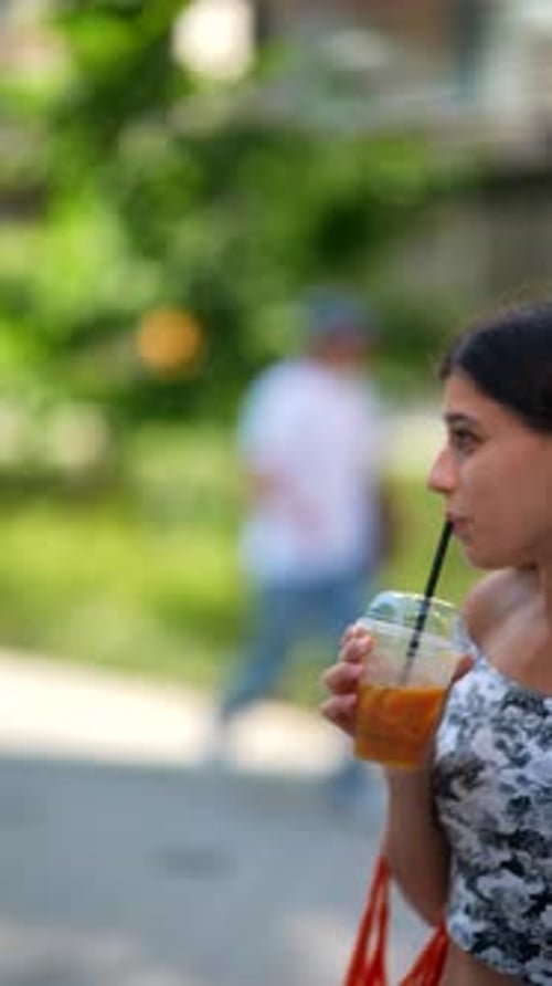 Young Woman Enjoys Drink Outdoors in City