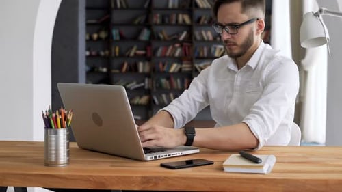 Man Working on Laptop at Desk in Home Office