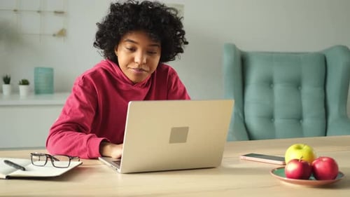 African American Girl Using Laptop at Home Office Looking at Screen Typing Chatting Reading Writing