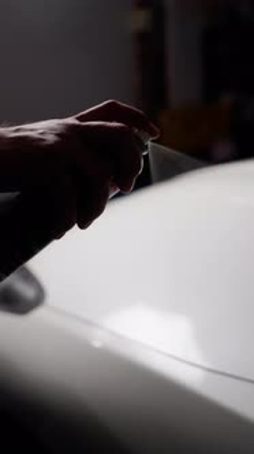 Spraying Aerosol on White Surface in Dim Light