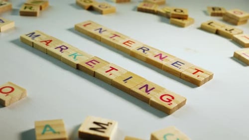 Holzbuchstaben, die Internet-Marketing buchstabieren, auf einem bläulich weißen Hintergrund mit anderen verstreuten Buchstaben