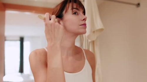 Woman Applying Makeup with Brush in Bathroom