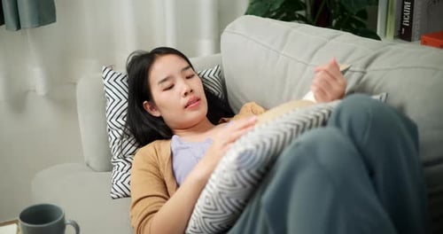 Young Woman Reads on Couch at Home
