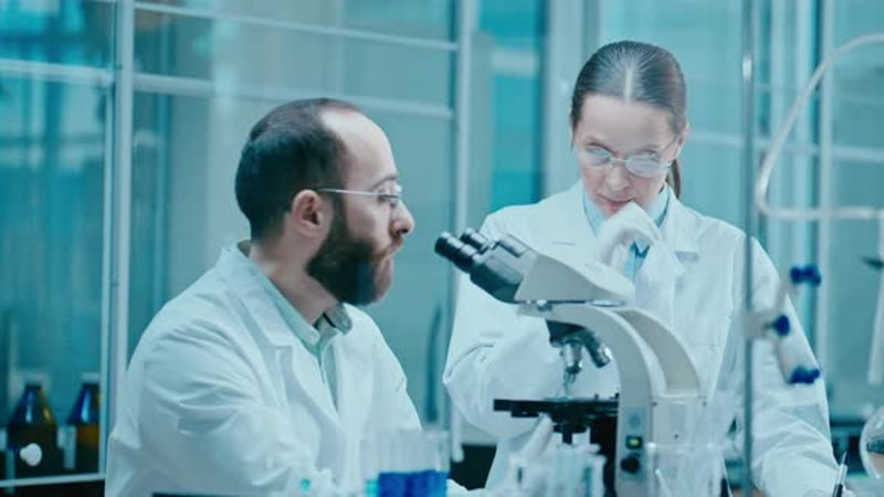 Female Lab Scientist Using Microscope and Talking in Research Center ...