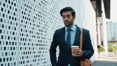 Young Businessman Walking and Using Phone on Street
