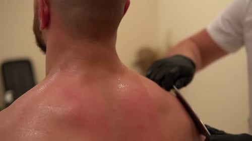 Close-up of Guasha Scraper Massage, Health care concept. Male person. Guasha shoulder massage