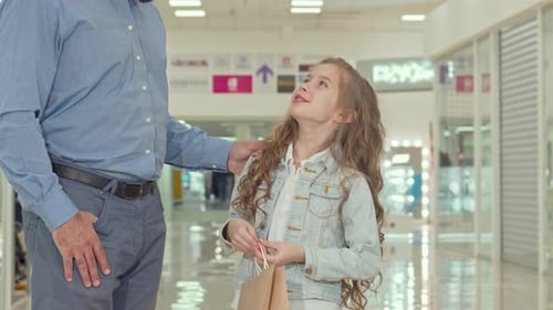 Joyful Little Girl Excitedly Pointing at a Kids' Store While Shopping with Her Father