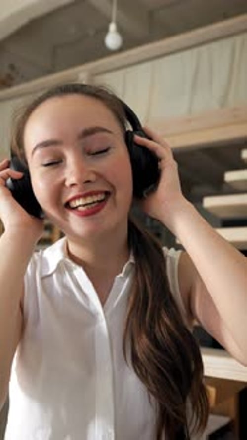 Young Woman Listening To Music on Headphones Indoors