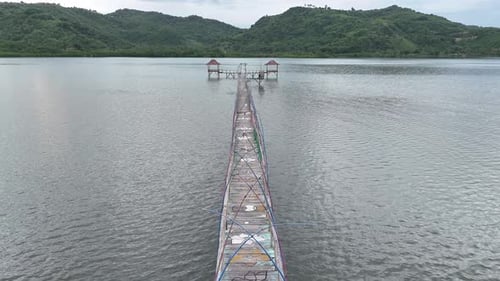 The bridge is made of wood that connects the house in the middle of the sea to the mainland.