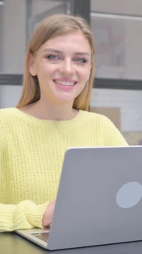 Smiling Woman Using Laptop at Desk in Workplace