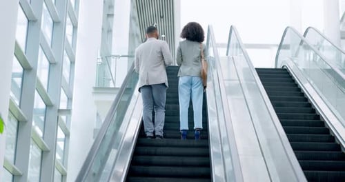 Man and Woman Riding Escalator in Modern Building