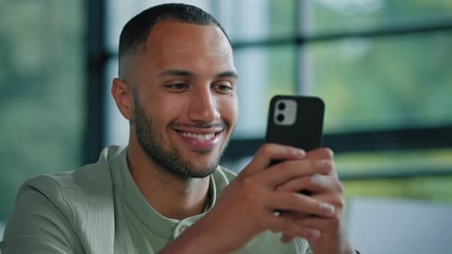 Smiling Man Using Smartphone Indoors