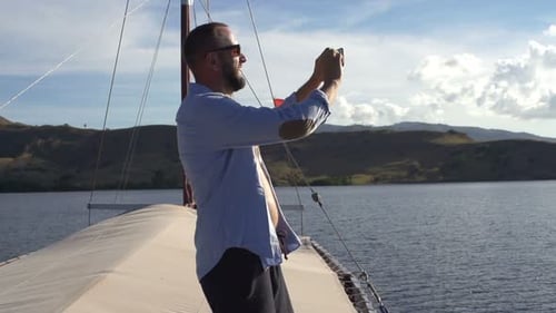 Man Taking Pictures on a Sailboat on Water