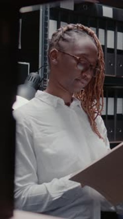 Woman Reviews Documents in an Office Filing Room