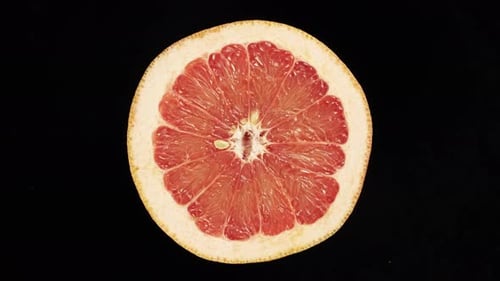 Rotierende Grapefruit im Querschnitt auf schwarzem Hintergrund.