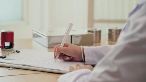 Doctor Writes on Medical Clipboard in Office