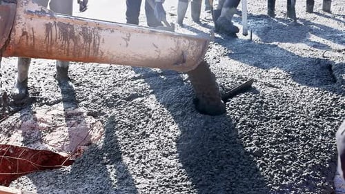 Arbeiter gießen am Werktag für Gebäudefundamente Betonmischung auf der Baustelle