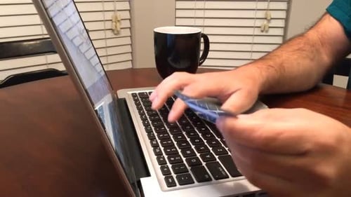 Man doing online shopping with credit card in hand before heading to work in the morning.