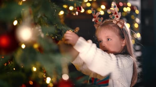 Cute Little Girl Putting Golden Heart on Christmas Tree Branch Portrait at Home Fabulous Miracle in