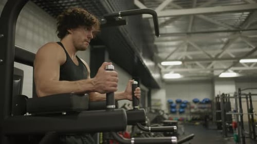 Athletic Man Performing Hanging Leg Raises during Core Workout in Gym