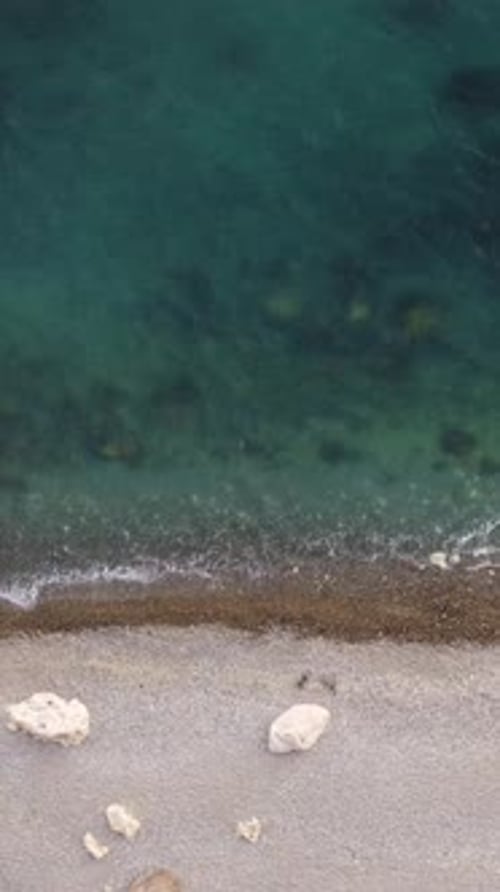 Aerial Vertical View of Beach with Wave Caressing Shore Sun Glare Small Waves on the Water Surface