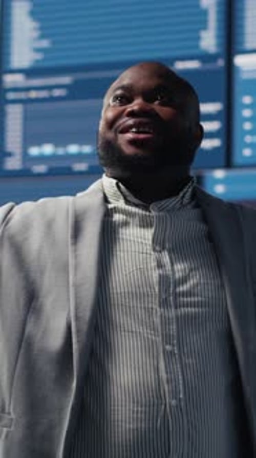 Man Stands in Front of Office Tech Monitors