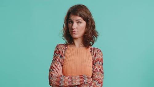 Serious Woman with Arms Crossed on Blue Background
