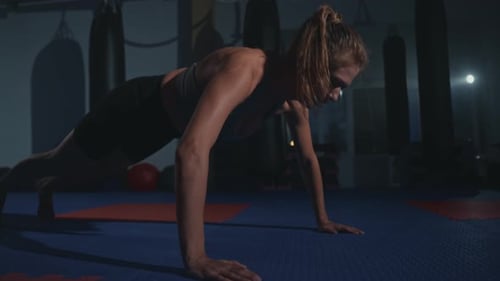 Intense Workout Session at a Dimly Lit Gym Focusing on Strength Training Exercises