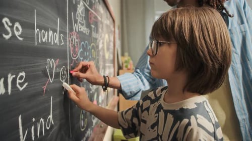 Young Teacher and Boy Drawing on Chalkboard in Modern Kindergarten Classroom