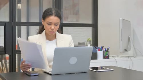 Concerned Woman Reviews Documents in Bright Office