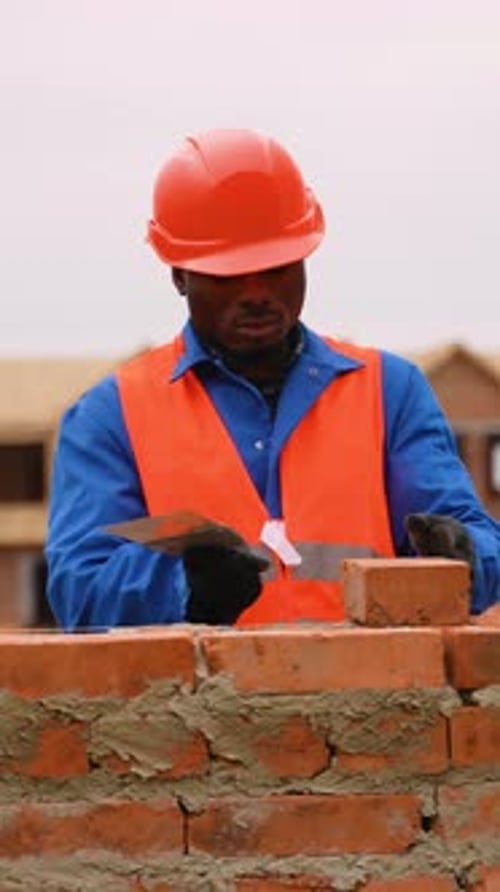African American Builder Laying Bricks at Townhouse Construction Site