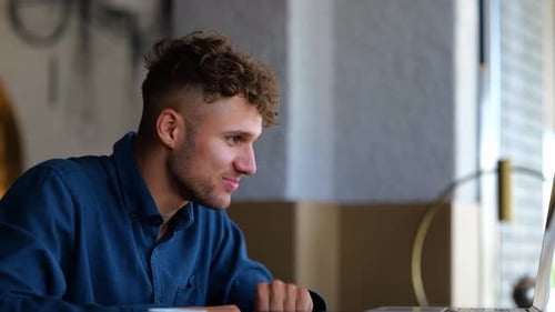 Close Up of Joyful Young Caucasian Man Smiling and Waving Hand Looking at Laptop Screen and Video