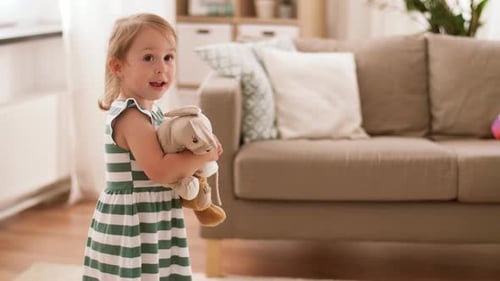 Smiling girl hugging stuffed animals in living room