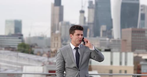 Businessman using smartphone looking out at London city skyline