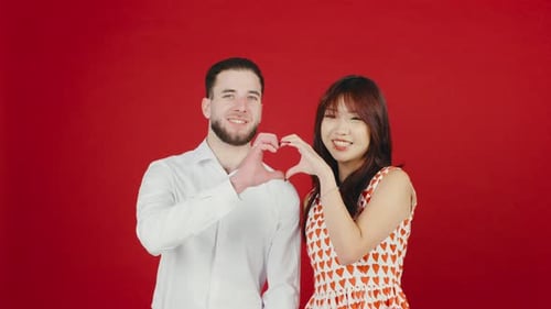 Happy Couple Making Heart Shape on Red Background