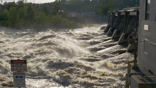 Waters browned out of hydro dam. From left danger keep out warning. very wide shot.