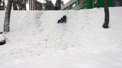 Child Sledding Down a Snowy Hill Having Fun During Winter Vacation