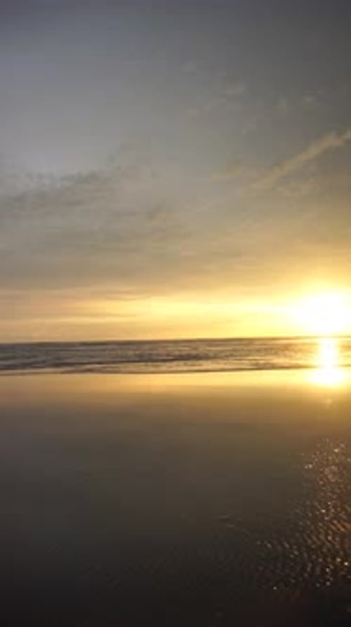 vertical video of beautiful views of the sunset on the beach with small waves, natural panorama