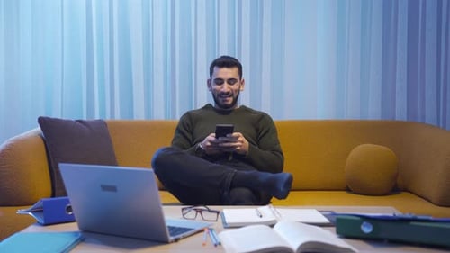 Man On Couch At Home Using Mobile Phone