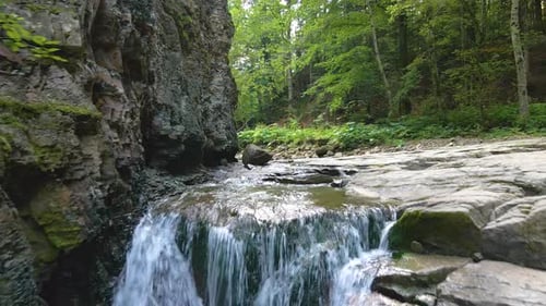 Waterfall on Mountain River with White Foamy Water Falling Down From Rocky Formation in Summer