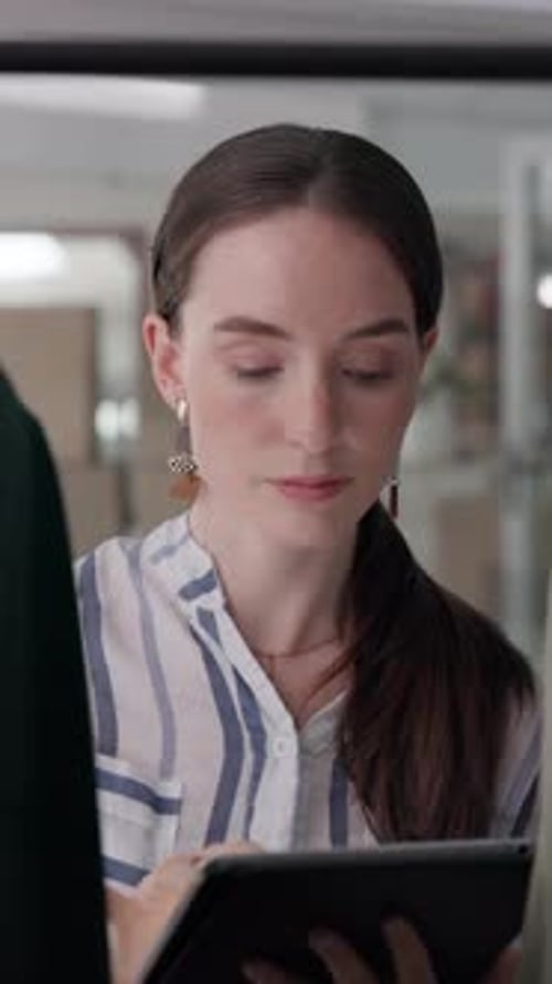 Woman Reviews Clothing Rack Using Tablet Indoors