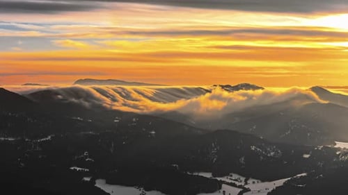 Golden Clouds Rolling Over Snowy Peaks