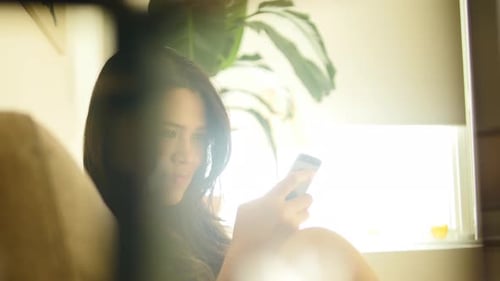 Woman Using Smartphone on Couch in Sunny Home