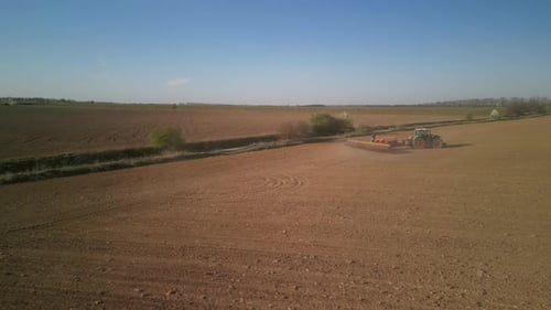 Green tractor works on the field sowing sunflower. Tractor planting corn in Ukraine