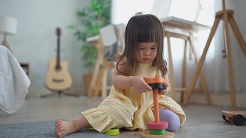 Веселая девочка играет с красочной игрушкой в уютной гостиной дома.